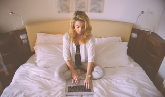Female sitting on a bed with a computer